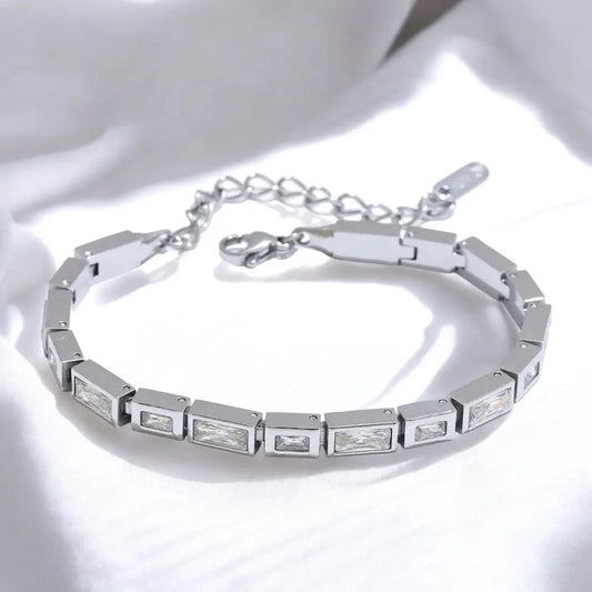 Silver bracelet with rectangular gemstones on a reflective surface