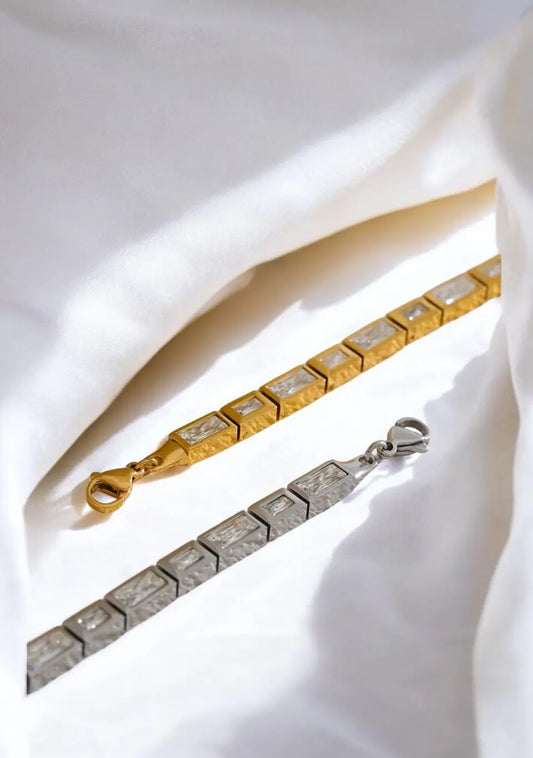 Gold and silver chain necklaces on a white fabric background