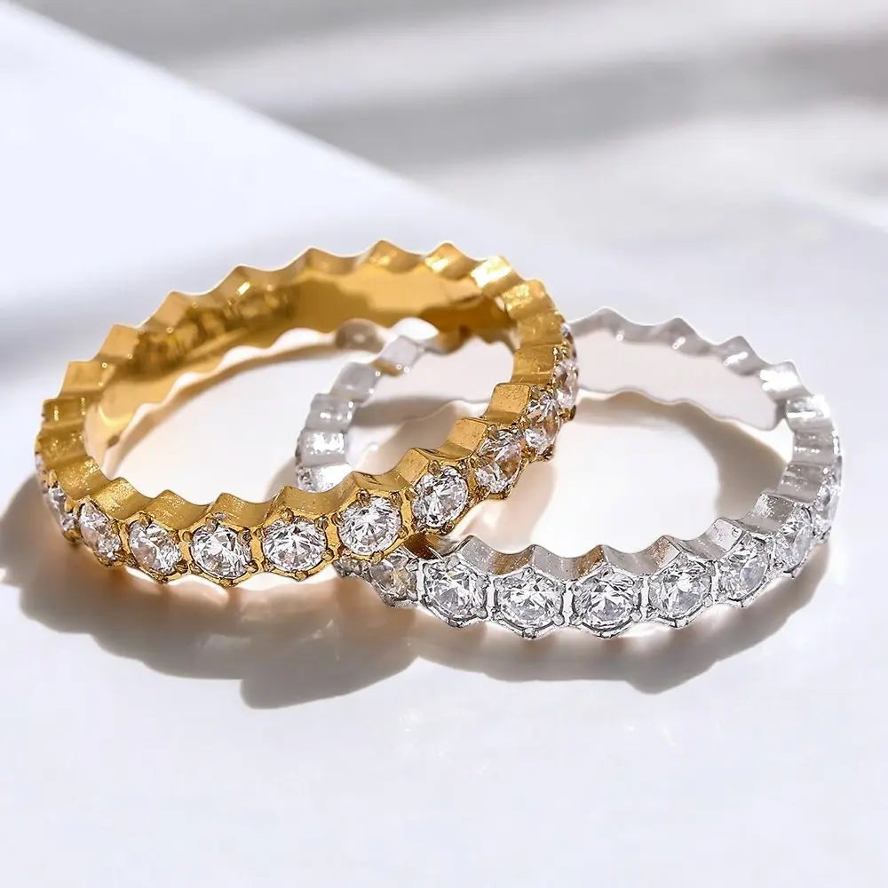 Two diamond eternity rings, one gold and one silver, on a light background