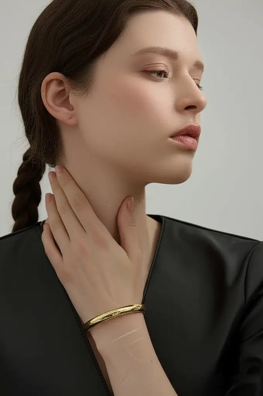 Woman wearing a gold bracelet on a plain background