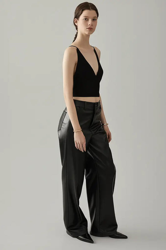 Woman wearing a black tank top and wide-leg pants on a gray background