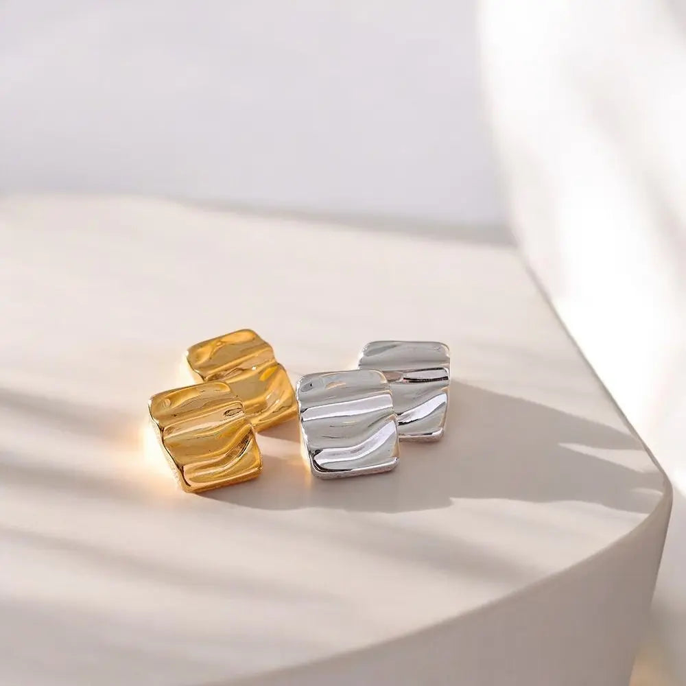 Gold and silver earrings on a white surface with a soft background