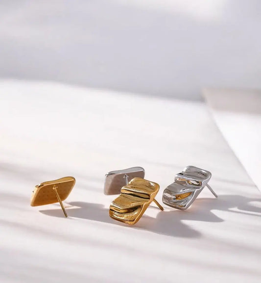 Pair of gold and silver earrings on a light surface