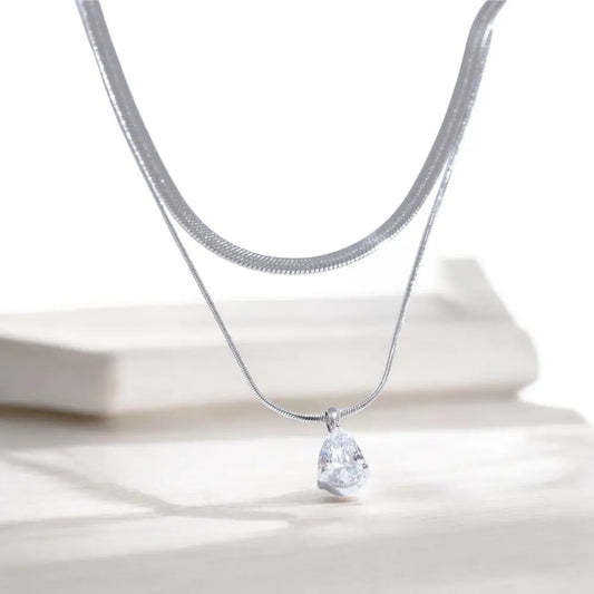 Silver necklace with a teardrop-shaped pendant on a white background