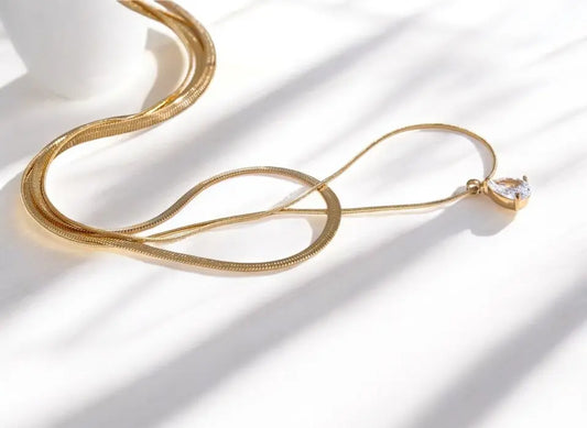 Gold necklace with a diamond pendant on a white background