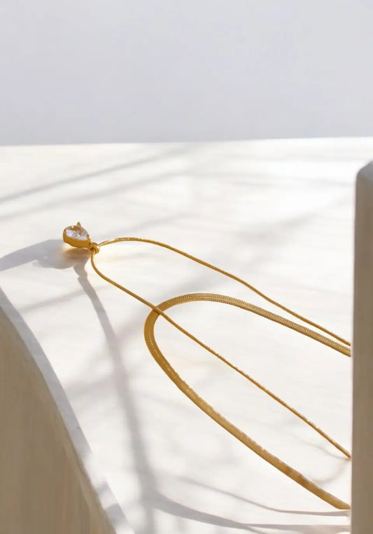Gold earring on a white surface with soft shadows