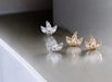 Pair of silver and gold earrings on a reflective surface