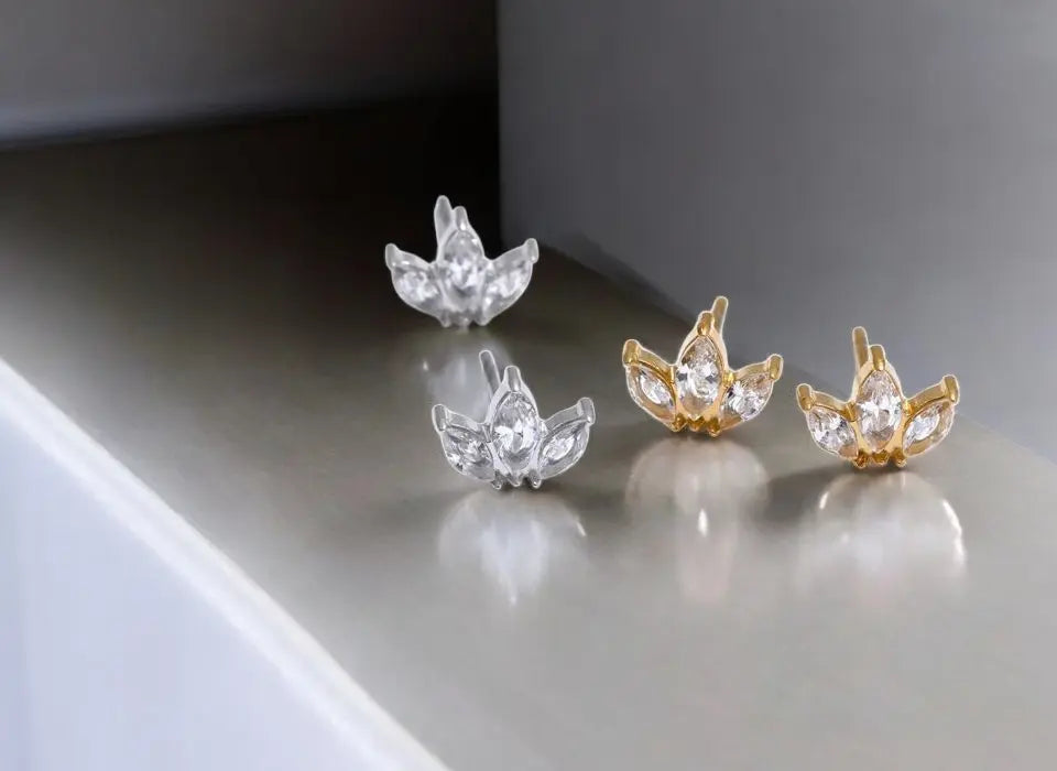 Pair of silver and gold earrings on a reflective surface