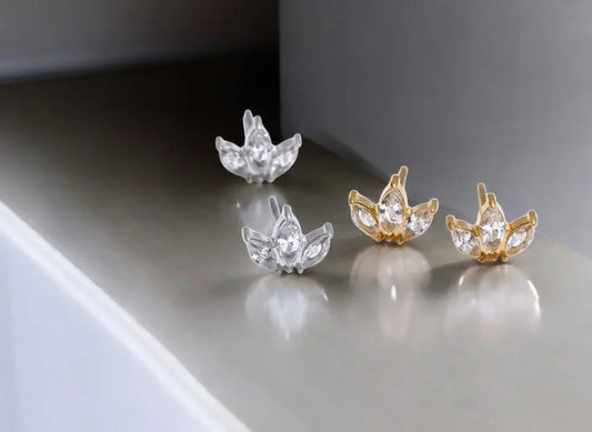 Pair of silver and gold earrings on a reflective surface