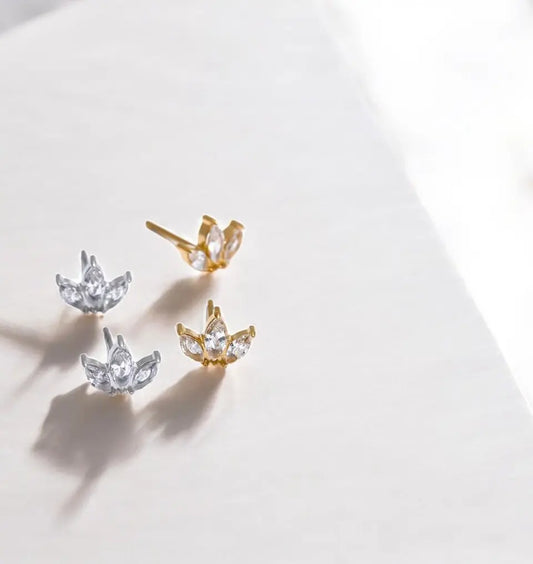 Pair of gold and silver lotus-shaped earrings on a light background