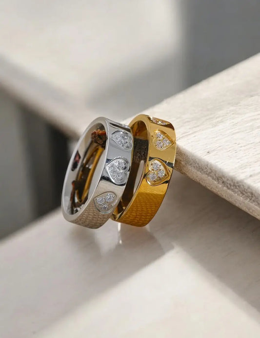 Two gold rings with diamond accents on a light wooden surface.