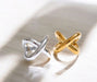 Two rings, one silver and one gold, on a reflective surface.