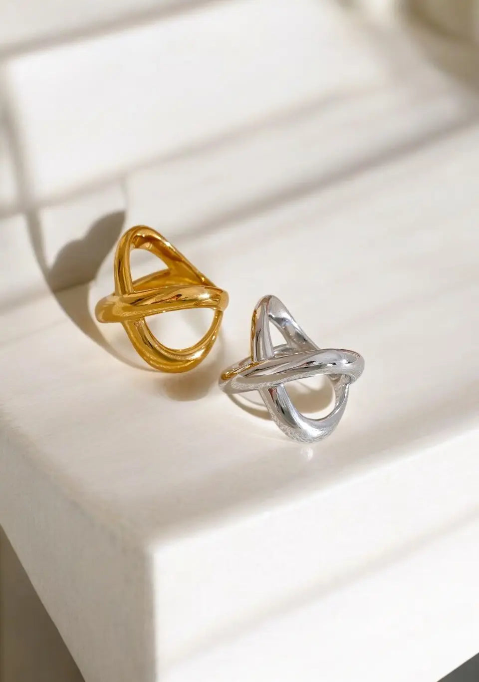 Gold and silver geometric earrings on a light surface