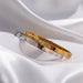 Three gold bracelets with diamond accents on a white fabric background