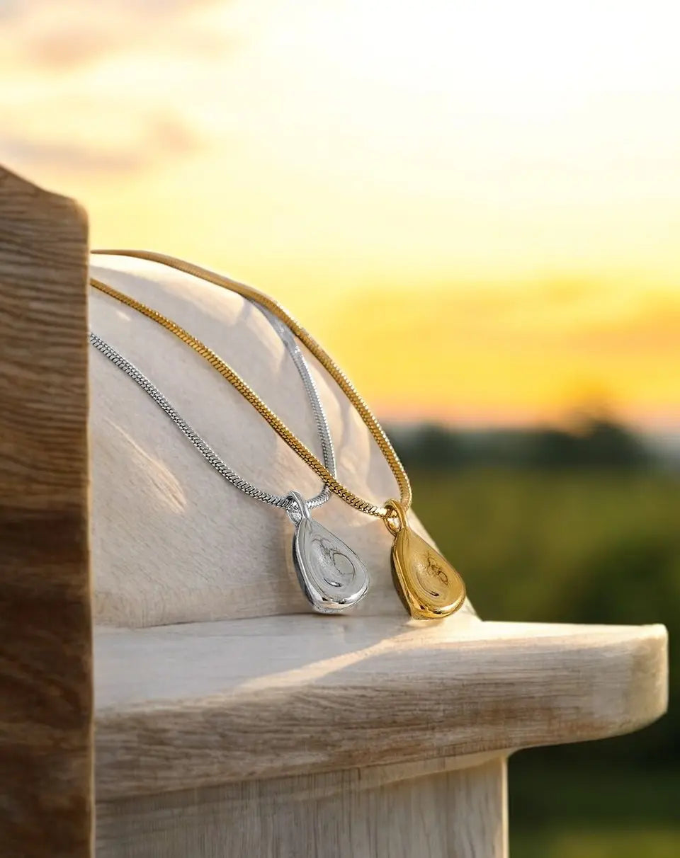 Two necklaces on a wooden surface with a sunset background