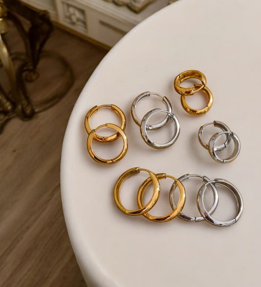 Gold and silver hoop earrings on a white surface with a blurred background