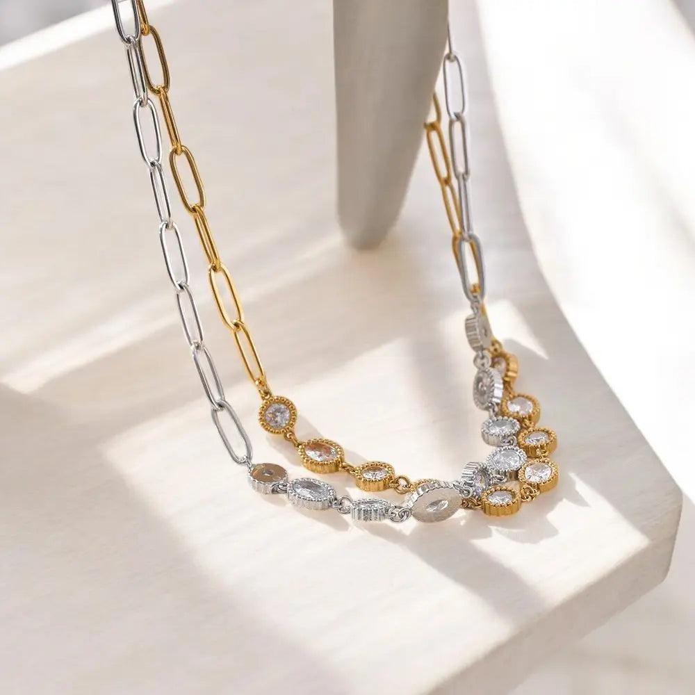 Gold and silver necklace with floral design on a light background