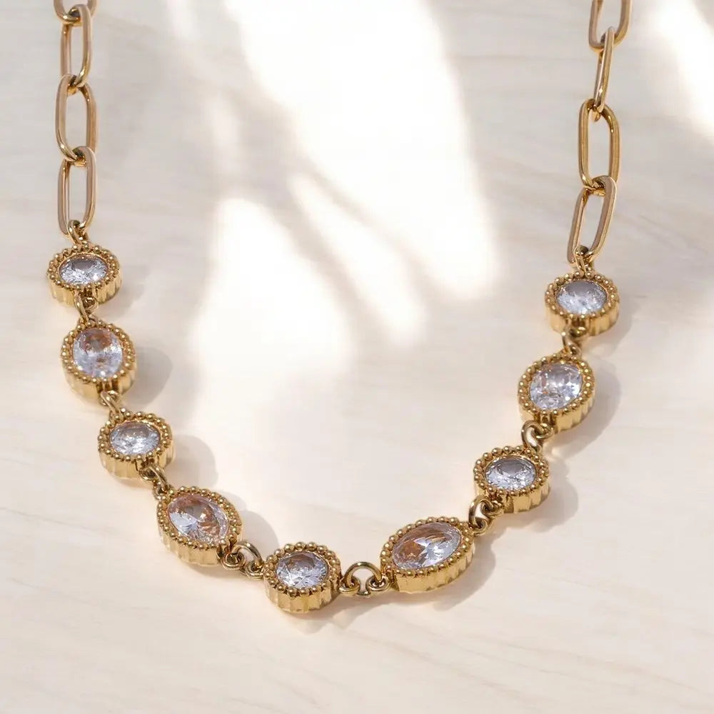 Gold chain necklace with crystal-like stones on a light background