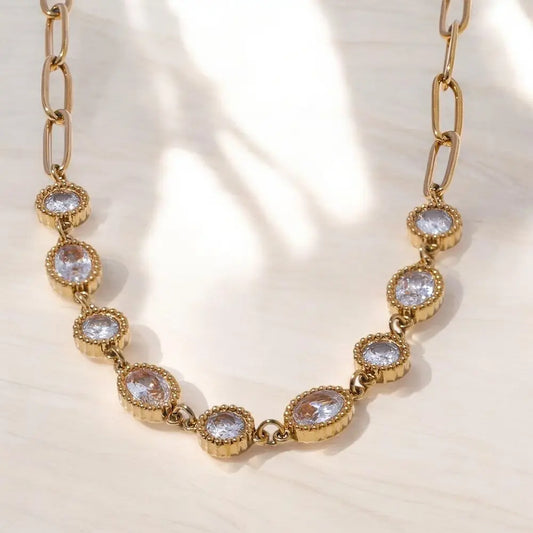 Gold chain necklace with crystal-like stones on a light background