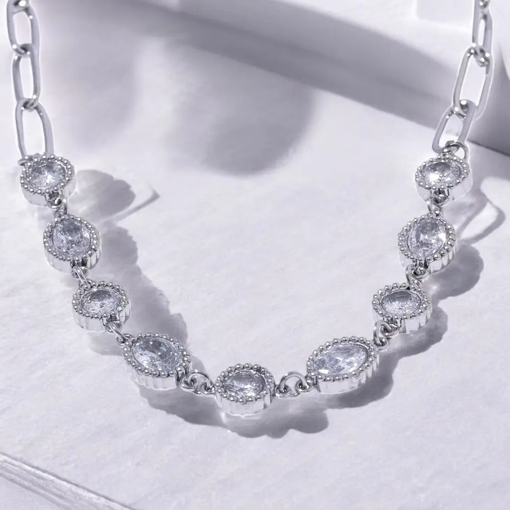 Silver necklace with clear gemstones on a white background