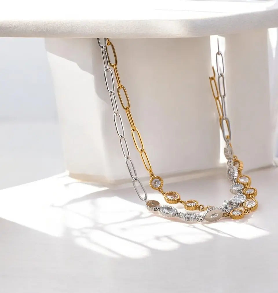 Gold and silver chain necklace on a white surface