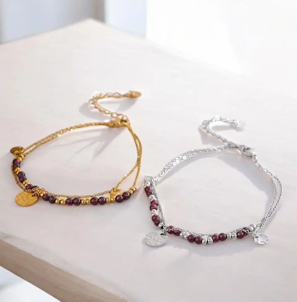 Two beaded bracelets, one gold and one silver, on a light surface.