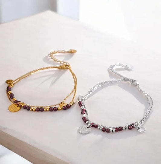 Two beaded bracelets, one gold and one silver, on a light surface.