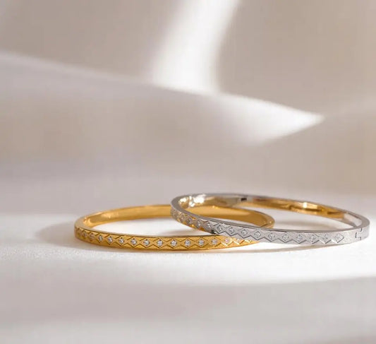 Two gold bangles with diamond accents on a light background