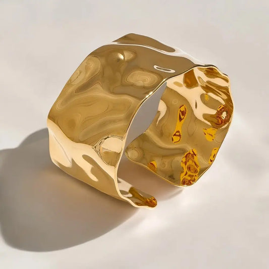 Gold cuff bracelet on a light background