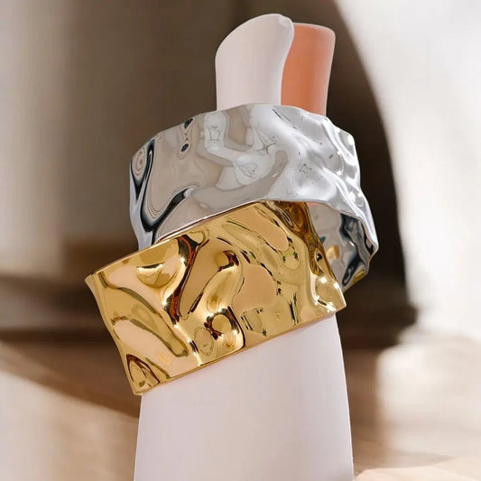 Gold and silver marbled cuff bracelet on a white stand with a blurred background