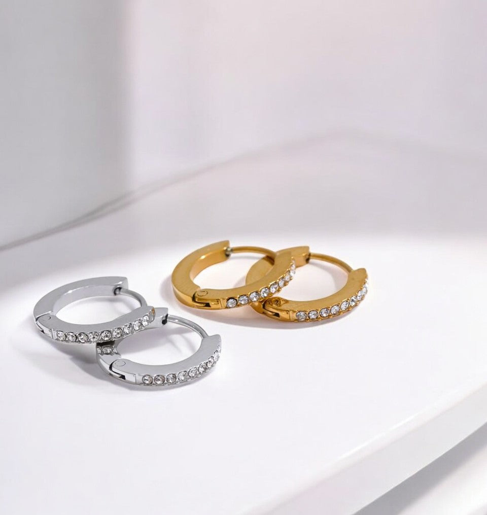 Two hoop earrings, one gold and one silver, on a light gray background