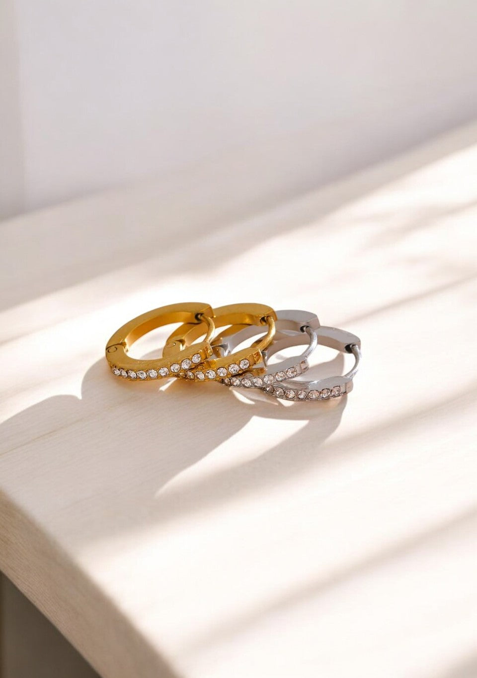 Three gold and silver rings with diamond accents on a light wooden surface.