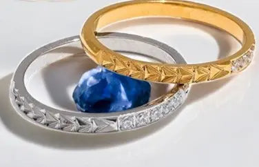 Two gold rings with a blue stone on a light background