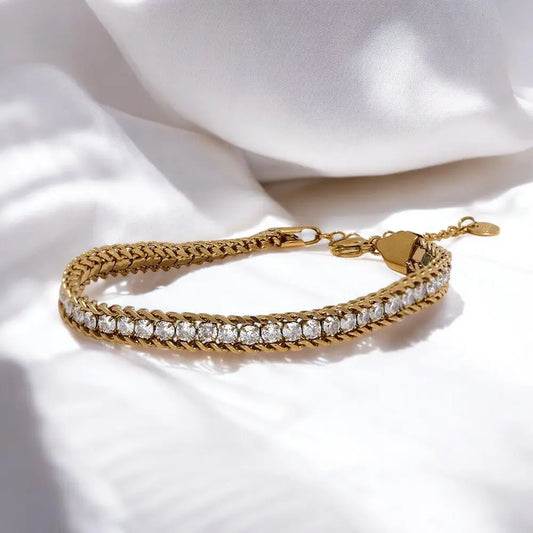 Gold bracelet with clear stones on a white fabric background