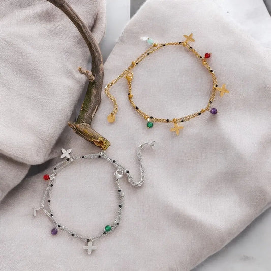 Two beaded bracelets on a soft fabric surface with a natural branch.