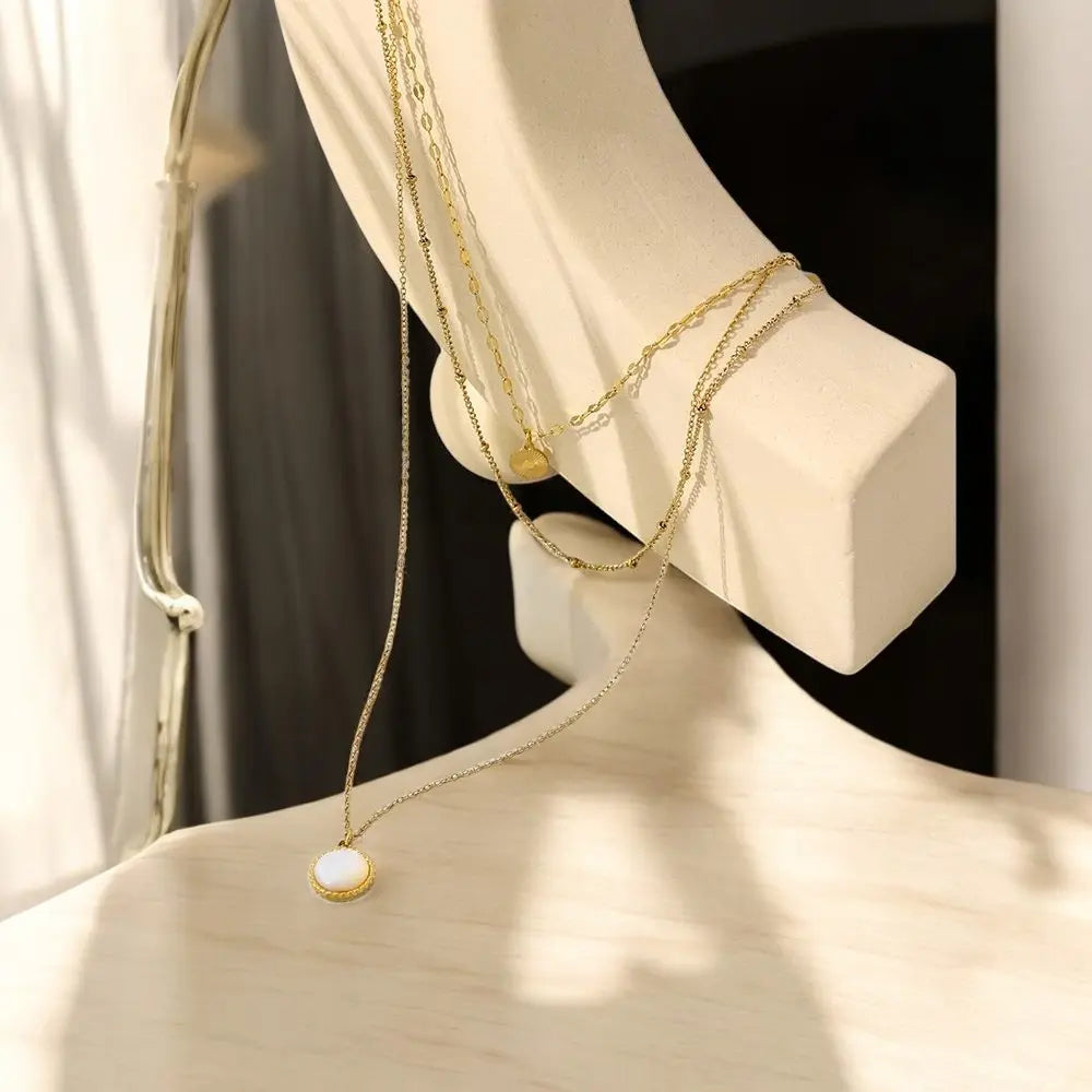 Gold necklaces on a mannequin bust with a neutral background