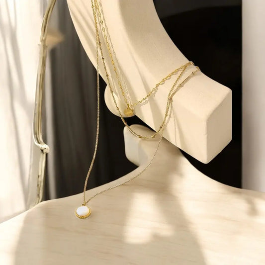 Gold necklaces on a mannequin bust with a neutral background