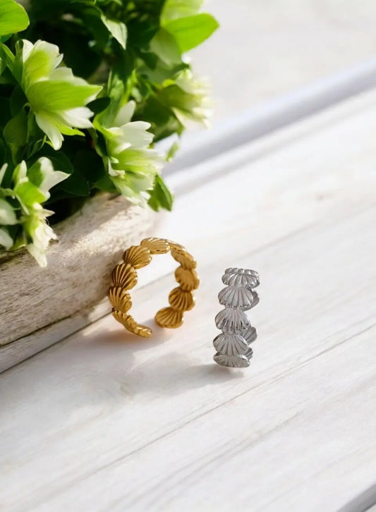 Gold and silver rings on a white surface with green leaves.
