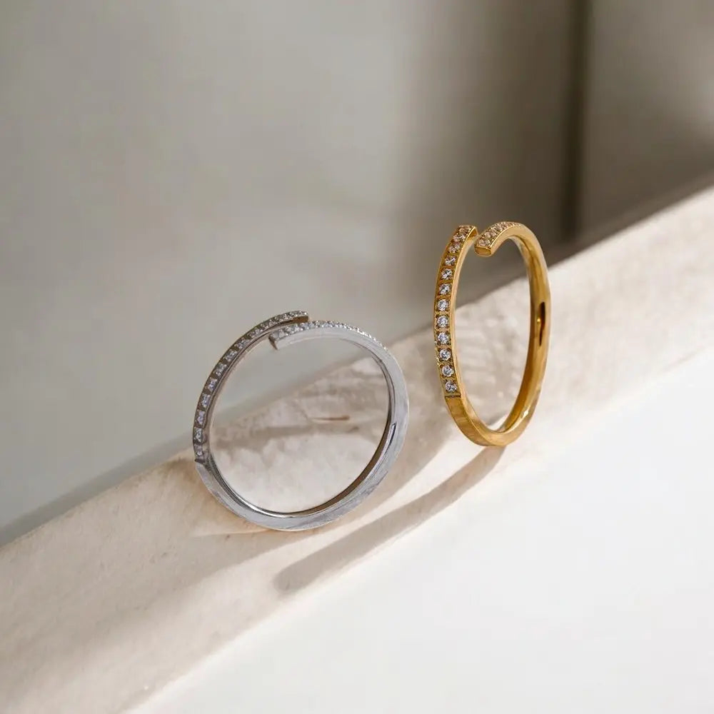 Two rings, one gold and one silver, on a light surface with a soft shadow.