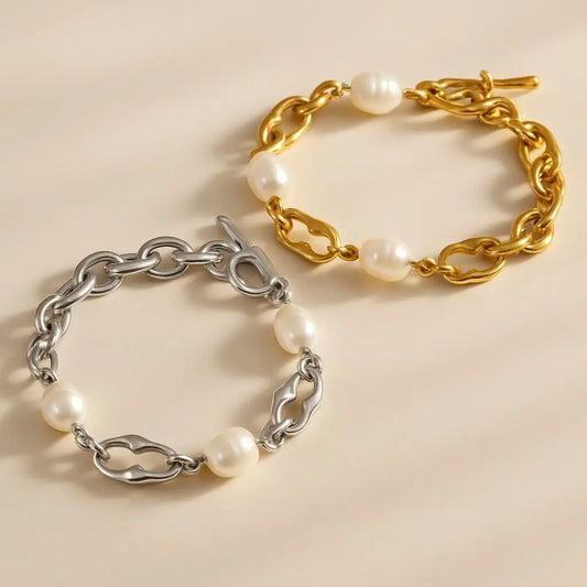 Two pearl and chain bracelets, one gold and one silver, on a beige background.