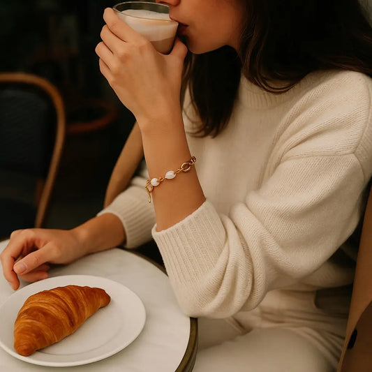 Person drinking coffee with a croissant on a plate