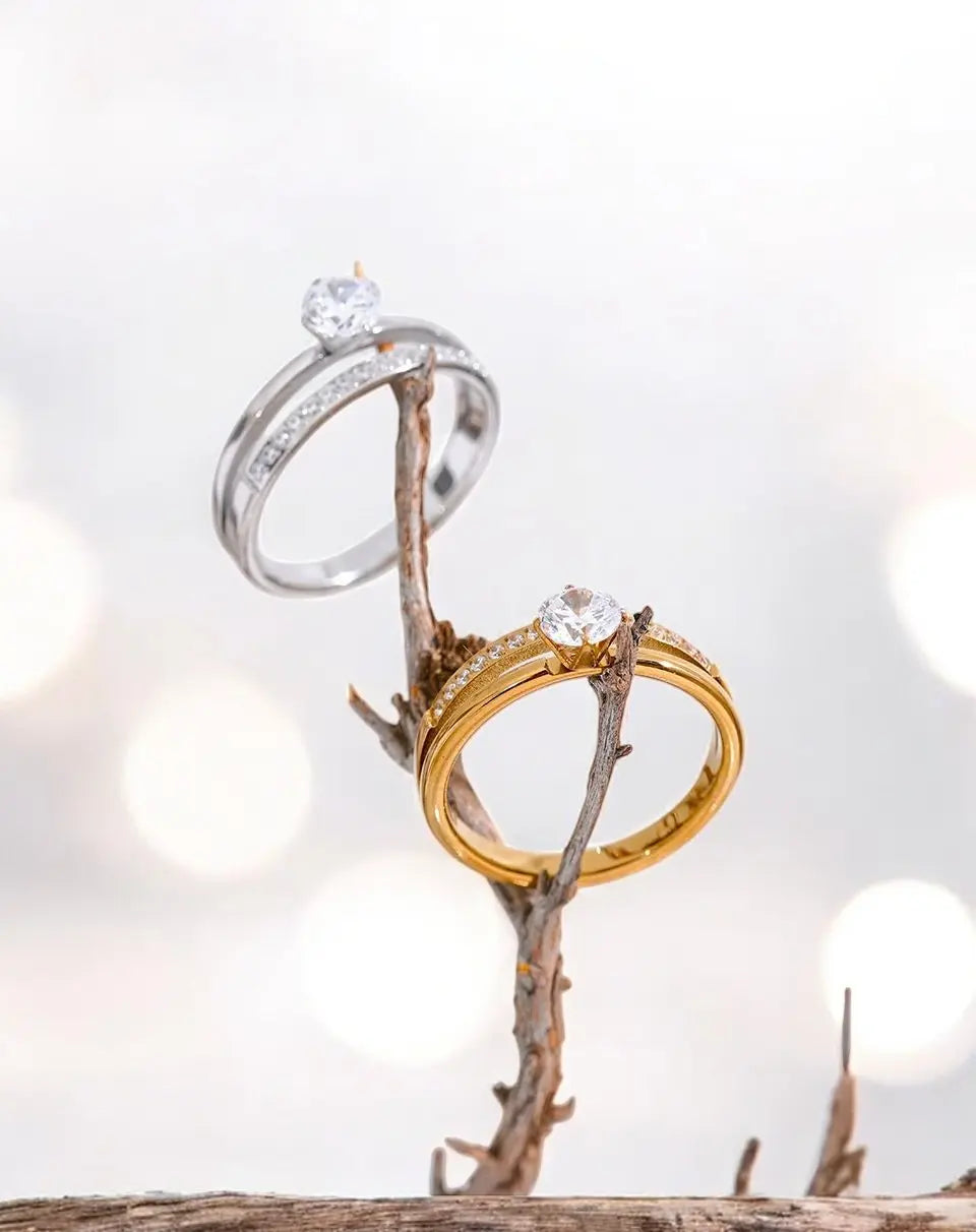 Two rings, one gold and one silver, on a branch with a blurred light background