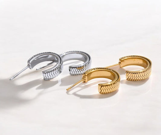 Pair of silver hoop earrings and gold hoop earrings on a light background