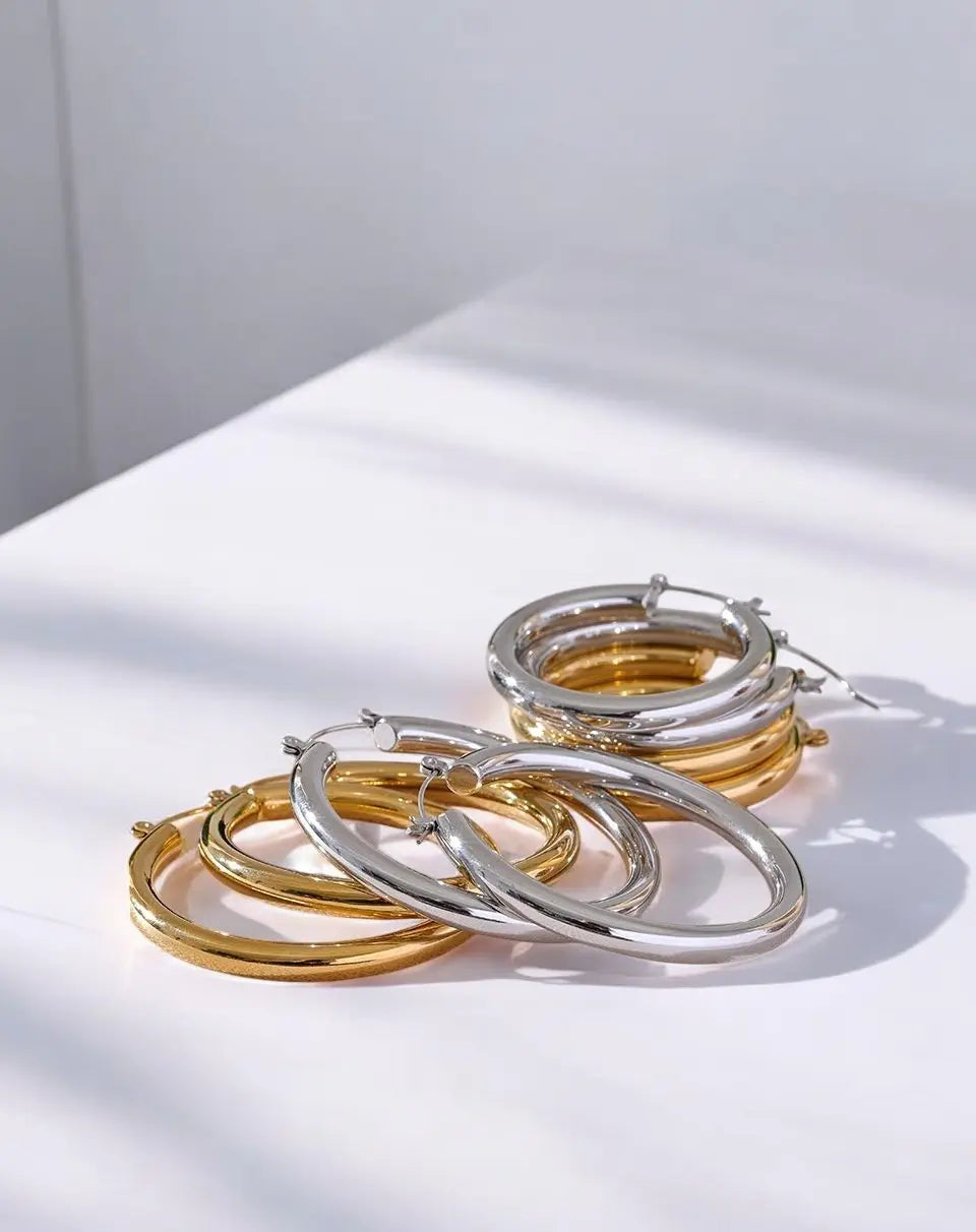 Three hoop earrings in gold and silver on a light background