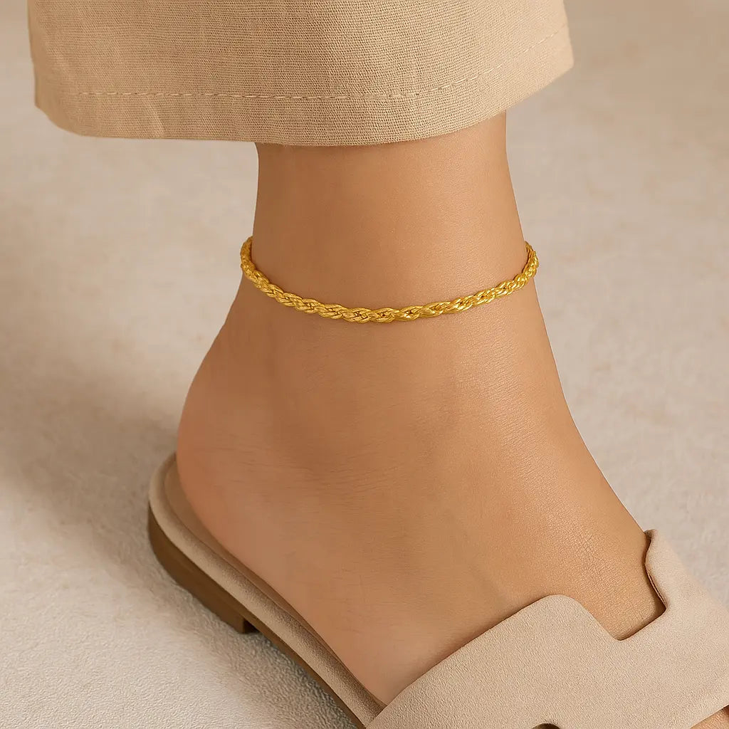 Gold anklet on a person's ankle with a neutral background