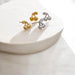 Gold and silver cherry-shaped earrings on a white surface