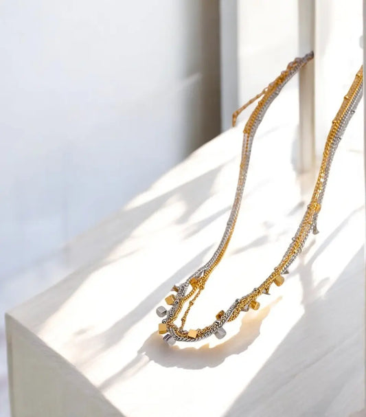 Gold necklace with small beads on a white surface