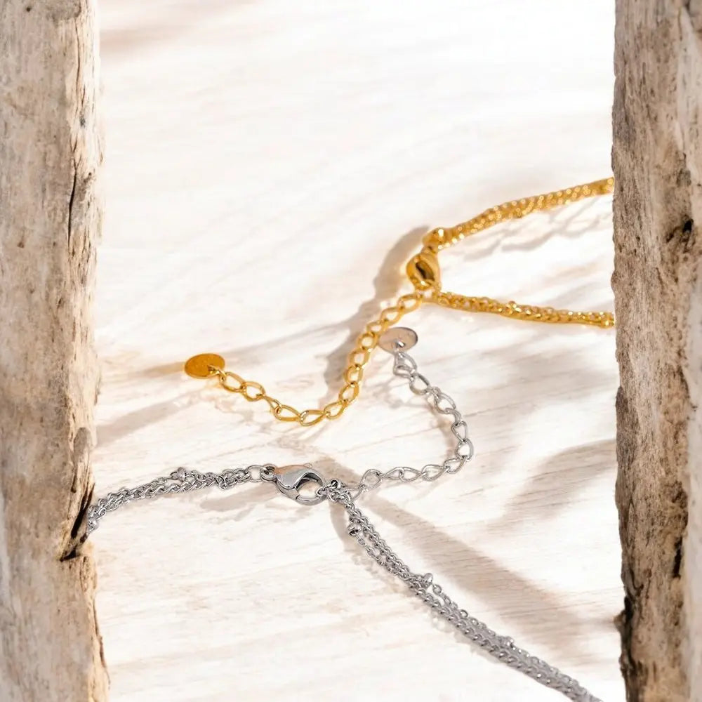 Gold and silver chain necklaces on a textured surface with natural light