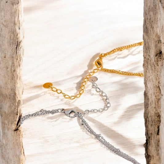 Gold and silver chain necklaces on a textured surface with natural light