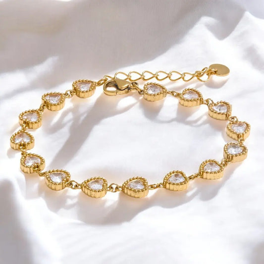 Gold bracelet with heart-shaped gemstones on a white fabric background